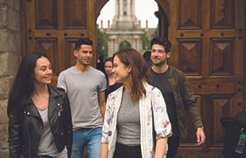 Four students walking out the entrance to Trinity on College Green