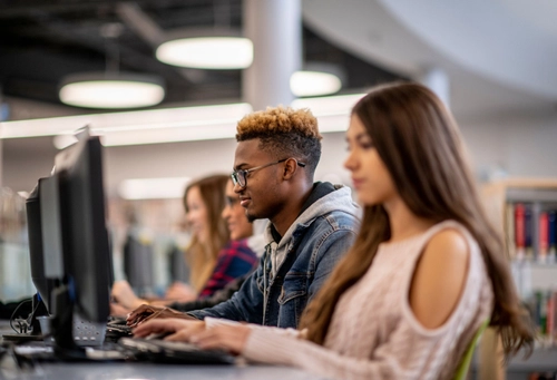 Four students sitting next to each other on computers