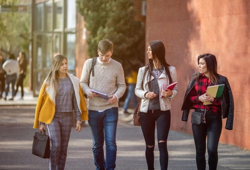 Four students walking together outside holding folders