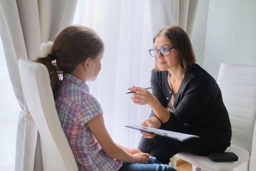 Mature female social worker with a child in an office