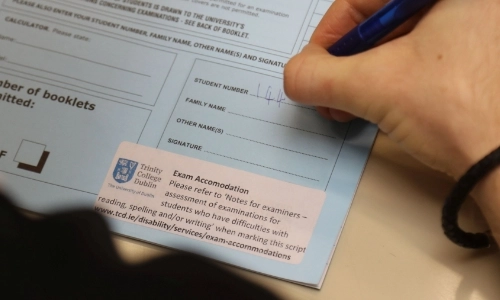 Exam Assistance with person writing on a blue exam paper