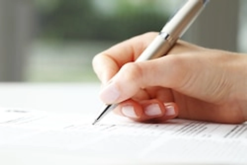 Person signing a document with a silver pen