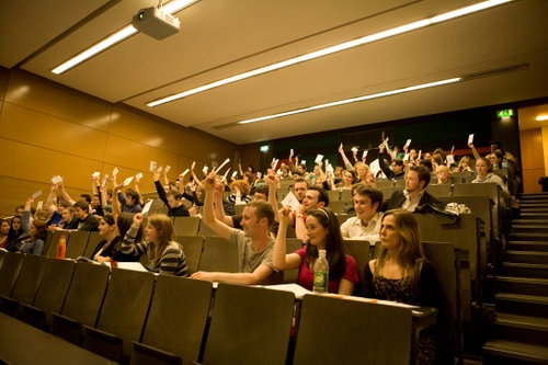 Students in a lecture theater holding up cards