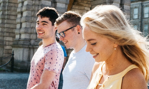 9 students sitting in groups of 3 around tables, talking
