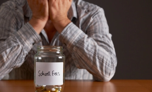 Socio economic issues where a worried person sits in front of a small jar of money