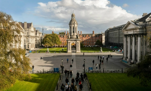 A photo of the Front Square in Trinity College Dublin with people walking through the square and the Campanile in the background