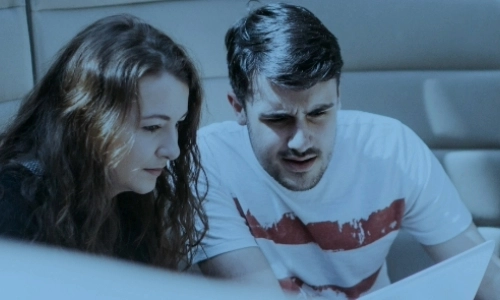 Two students looking at something on a computer, The image has a blue colouring over it