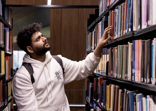 Student looking library shelves