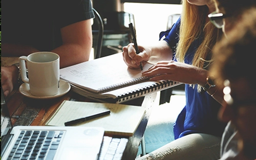 Students around a table covered in note books