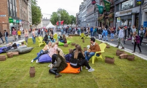 People sitting on artificial grass on College Green