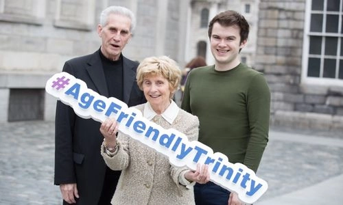 Two older people and a young man, the woman holds an '#AgeFriendlyTrinity' sign.