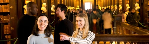 A group of visitors in the Old Library, talking and pointing.