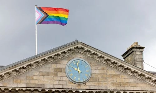 A pride flag on a flagpole above Trinity's main entrance.