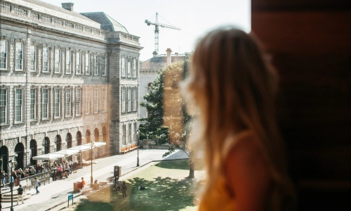 A student looking out a window at the Old Library.