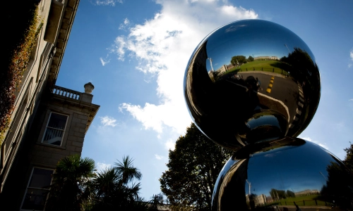 The Pomodoro sphere against a blue sky.