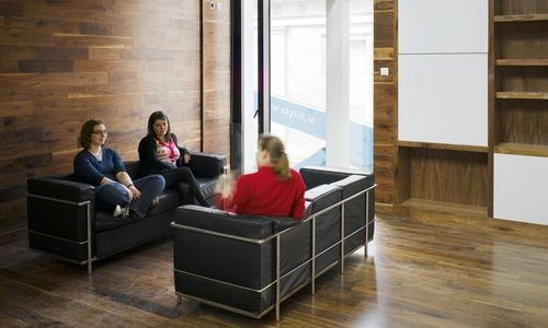 Three people seated on couches in the Long Room Hub.