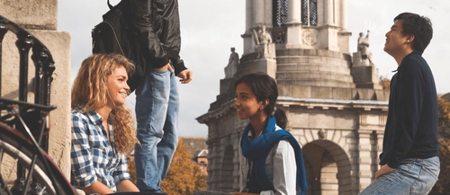 International students in conversation in front of the Trinity College Dublin campanile.