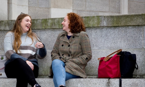 Two postgraduate students seated in conversation on Trinity campus.