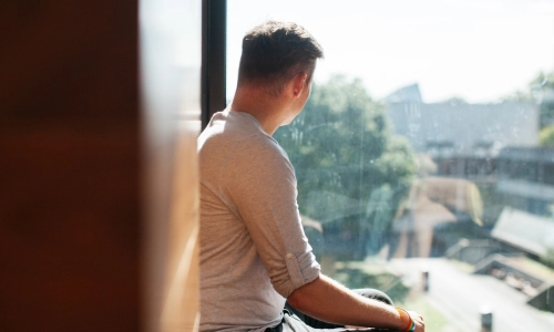 A student looking out a window onto Fellow's Square.