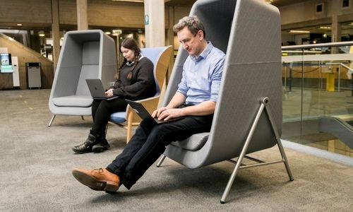 Two people working separately on laptops in the Eavan Boland Library.