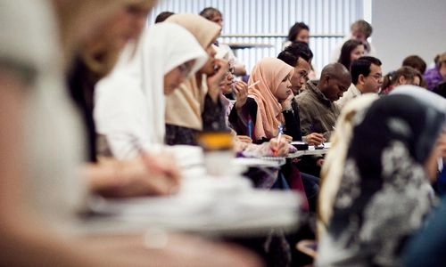 Students taking notes in a busy lecture room.