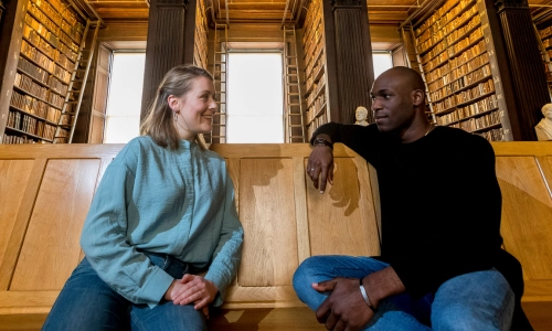 Two students sitting in Trinity's Old Library.