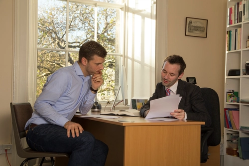 Academic discussing with a student around a desk