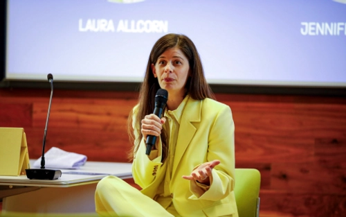 Woman in yellow suit speaking with mic