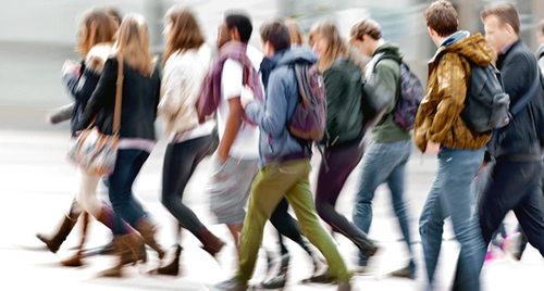 Group of college students walking through Trinity College campus.
