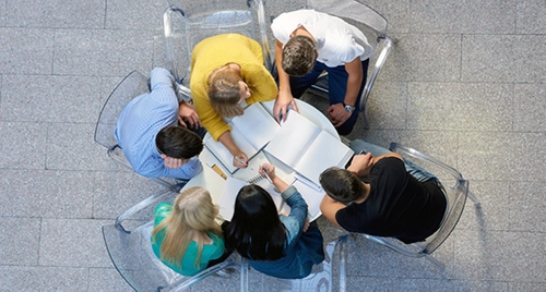 Group of college students sitting at a small table working together.