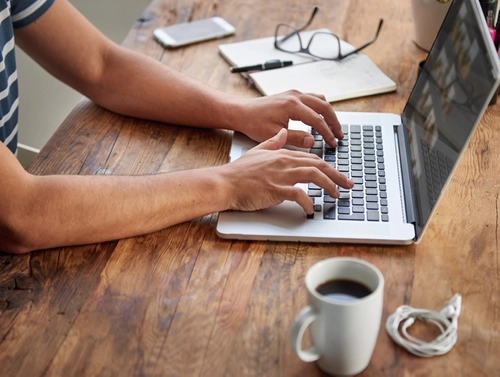 Person working on laptop at a desk.