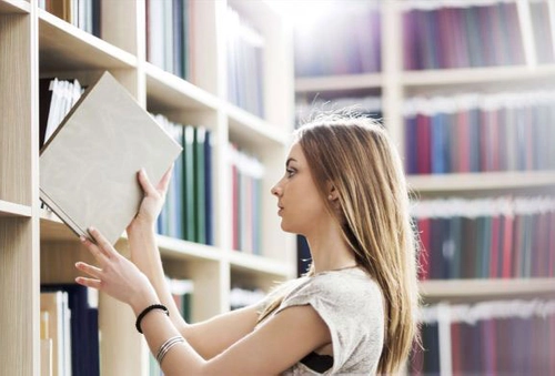 A student taking a book from a library shelf