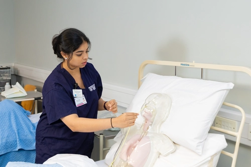 students treating a dummy patient in bed
