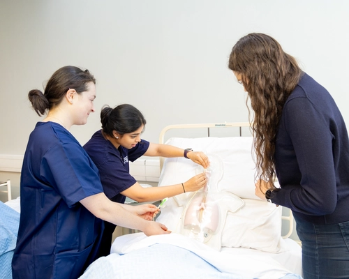 students treating a dummy patient in bed