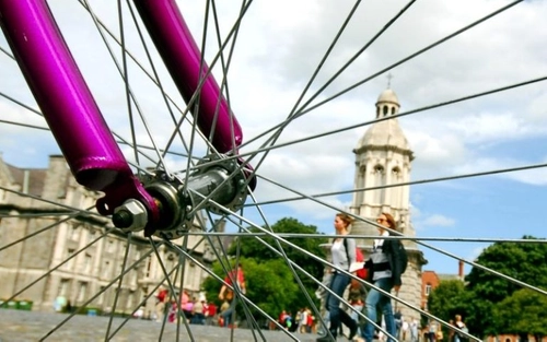 View of trinity campus campanile and building through bicycle spokes