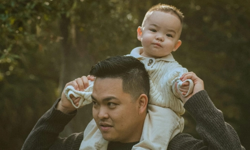 Father holds child on his shoulders