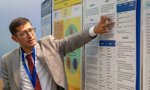 Male presenter pointing at poster