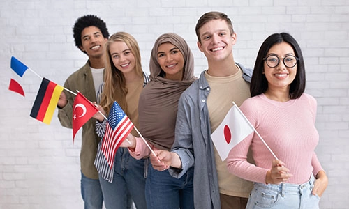 Exchange students and language school for different people. Funny digital young international pupils holding flags of USA, Japan, Turkey, Germany and France in classroom, studio shot, empty space