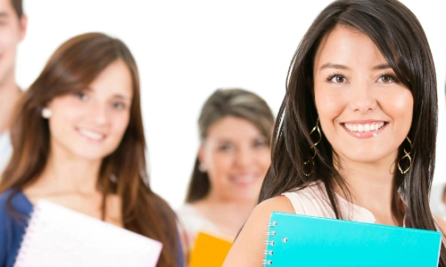 Three students looking at the camera, holding books