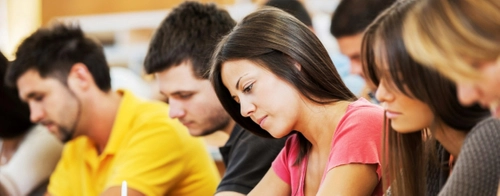 Seven students taking notes in a lecture threatre