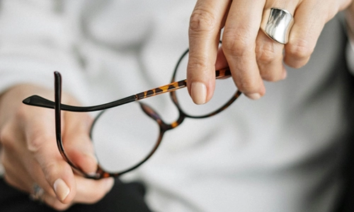 closeup of hands holding reading glasses