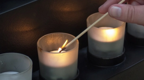 Image of a person lighting a candle in remembrance