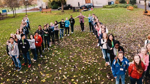 Image of students from the Walton club in a V shape standing on a grassy area