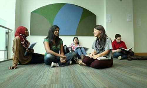 Five students sitting on the floor chatting
