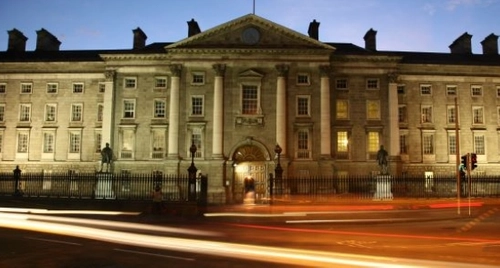 An image of TCD College Green in the evening with traffic passing by