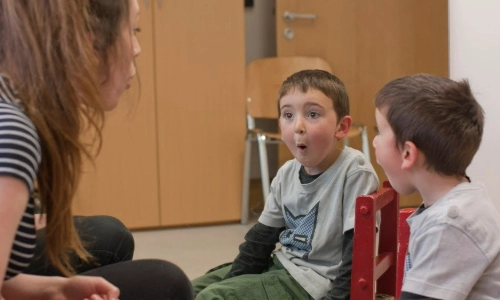 A teacher teaching two young children how to pronounce the letter O