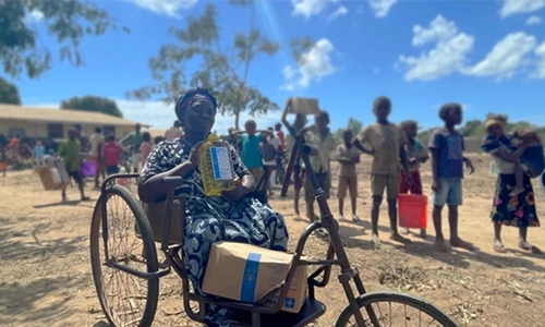 An image many people celebrating and a person on a bike in the foreground