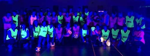 UV Sports Day shwoing people in bright clothing lit up under UV lights
