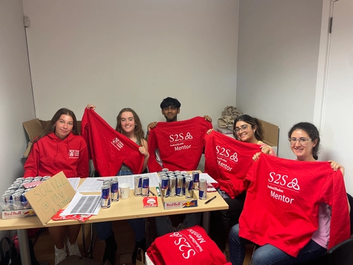A group of 5 students holding up red hoodies that say 