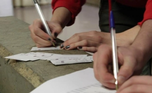 Two people ticking boxes on paper